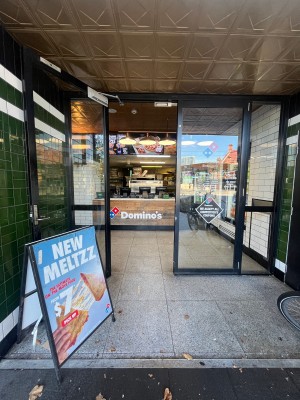 Glass double doors with black metal frame. Turn silver handle and pull left door from middle. A-frame sign obstructing to left.