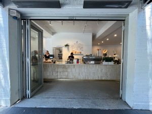Glass door with silver metal frame folds open to left.