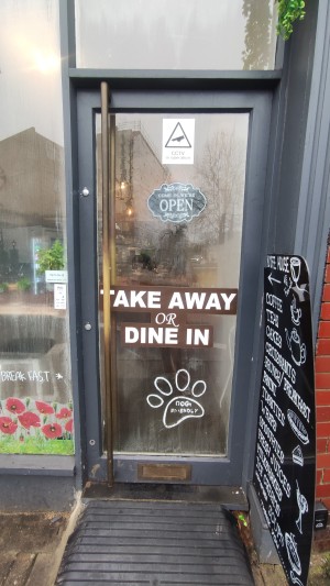 Glass door with grey frames. Push handle on left to open.