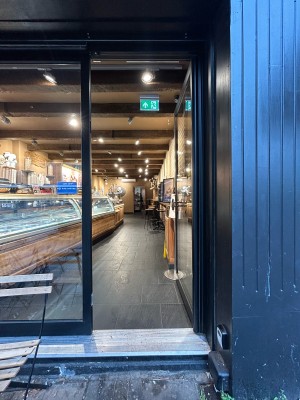 Glass door with black frame. Push black metal handle on left to open.