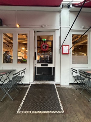 Glass door ahead with black and white frame. Push from left to open.