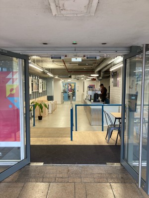 Glass doors with metal frames ahead. Pull doors to open via metal handrails in center.