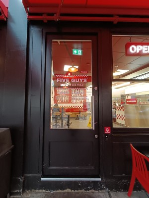 Glass door with black frame. Push silver, metal handle on right to open. Doorbell on right door frame.
