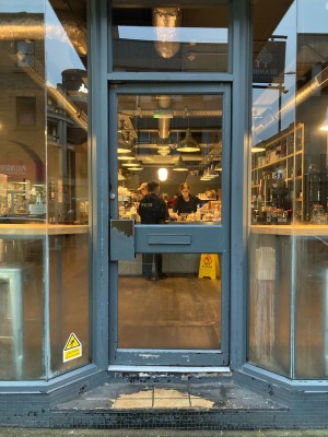 Glass door with metal frame ahead. Push door to open via handle on left.