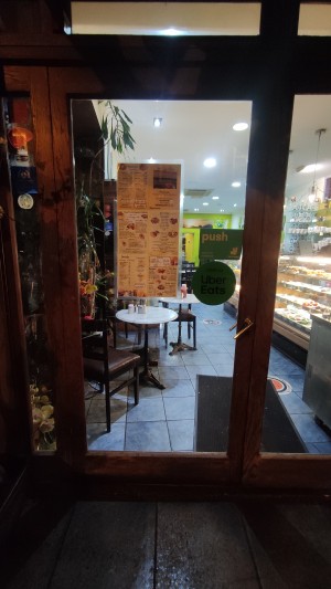 Glass door with brown frames. Push metal handle on right to open.