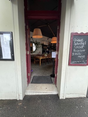 Glass doors with dark red wooden frame ahead. Push from centre to open.