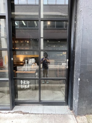 Glass door with black metal frame slides open to left using silver handle on right.