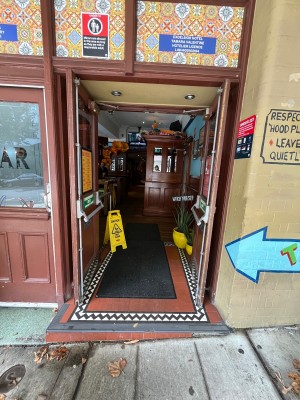 Glass double doors with brown wooden frame. Push from grey metal bars in middle.