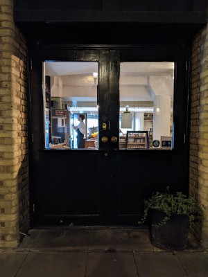 Glass and black wood doors with metal handles in centre. Pull to open.