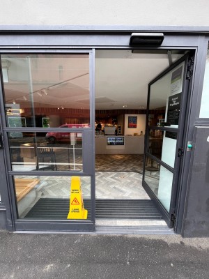 Glass double doors with black metal frame. Push from middle.