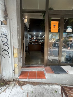 Glass door with brown metal frame. Push from right to open.