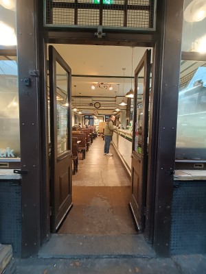 Glass doors with brown, wooden frames. Push, golden metal handles in middle to open.