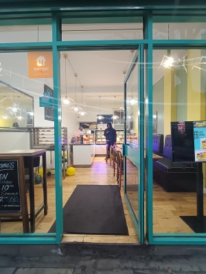 Glass door with blue frame. Push blue, metal handle on left to open.
