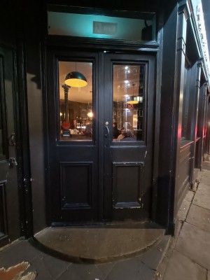 Glass door with black frame. Push silver, metal handle in middle to open.