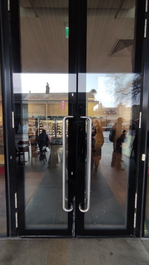 Glass doors with black frames. Pull metal handles in centre to open.