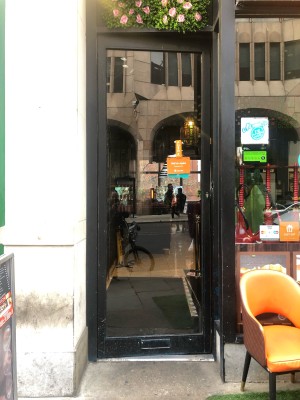 Glass door with black frame. Push on right to open.