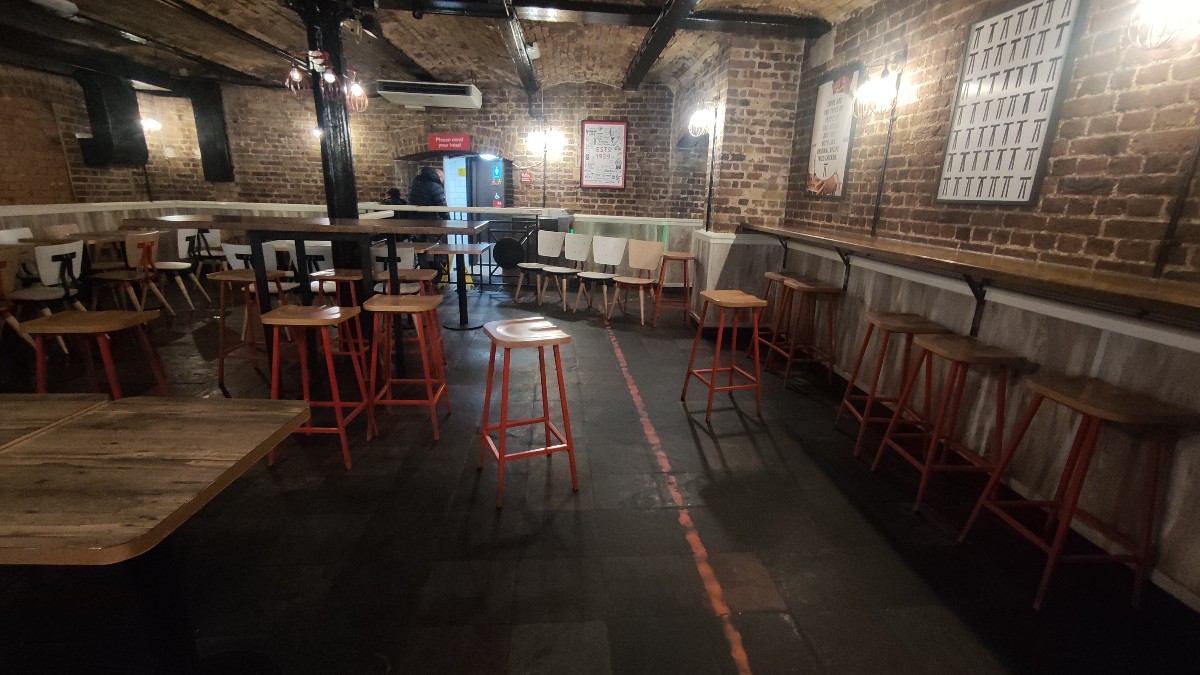 From after self ordering screen facing left. Tables and chairs along left. High tables and stools to back left and right.