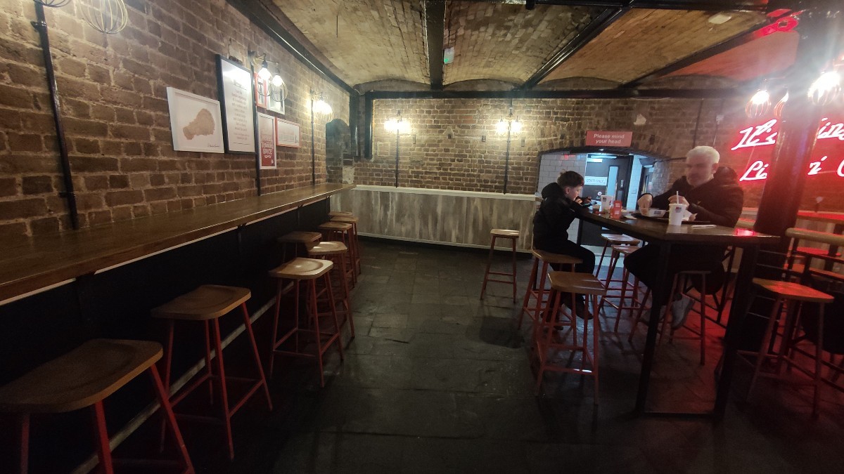From opening facing left. High tables and stools along left and right.