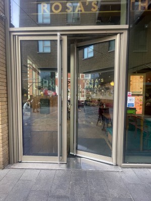 Glass doors with beige frame ahead. Push silver metal handles in centre to open.