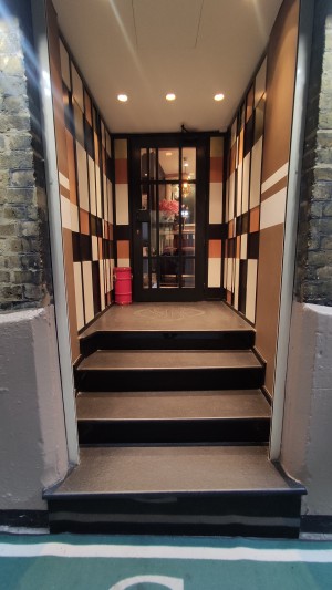 From pavement facing venue. Open doorway ahead. Four steps up to door.