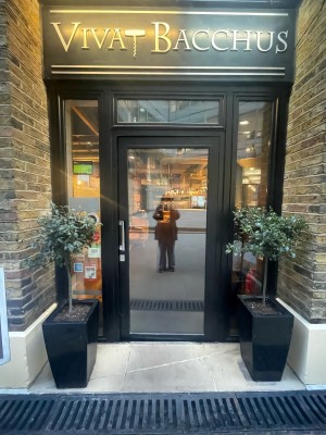 Glass door with black frame ahead. Push silver metal handle on left to open.