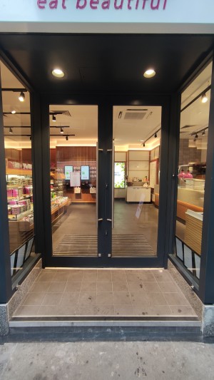 Glass doors with black frames ahead. Pull metal handles in centre to open.