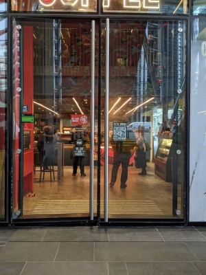 Glass doors with black frame and metal handles. Push from centre to open.