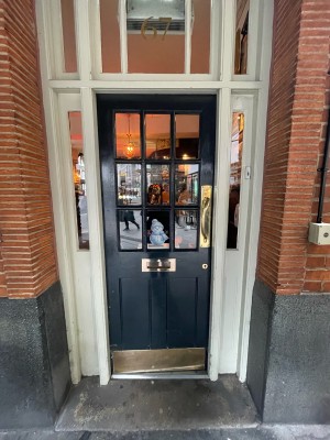Black glass and wooden door ahead. Push gold metal handle on right to open.