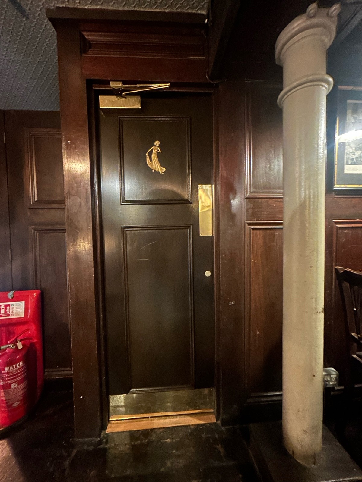From left of upstairs area facing left. Dark preceding wooden door ahead. Push from right to open.