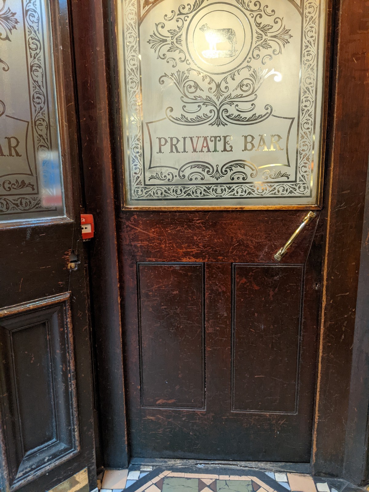 From first door facing straight. Glass and wood door with wood frame ahead. Push from metal handle on right.