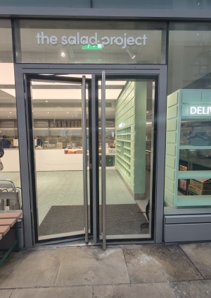 Facing grey framed glass doors. Push silver handles in centre to open.
