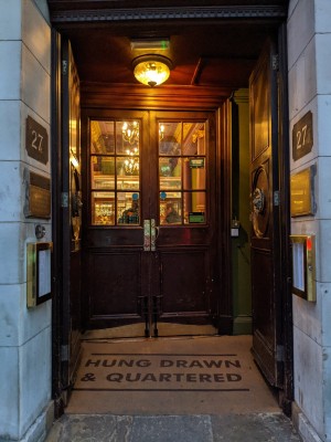 Wood doors with stone frame and metal handles in centre. Push to open. Doorbell to left of doors.