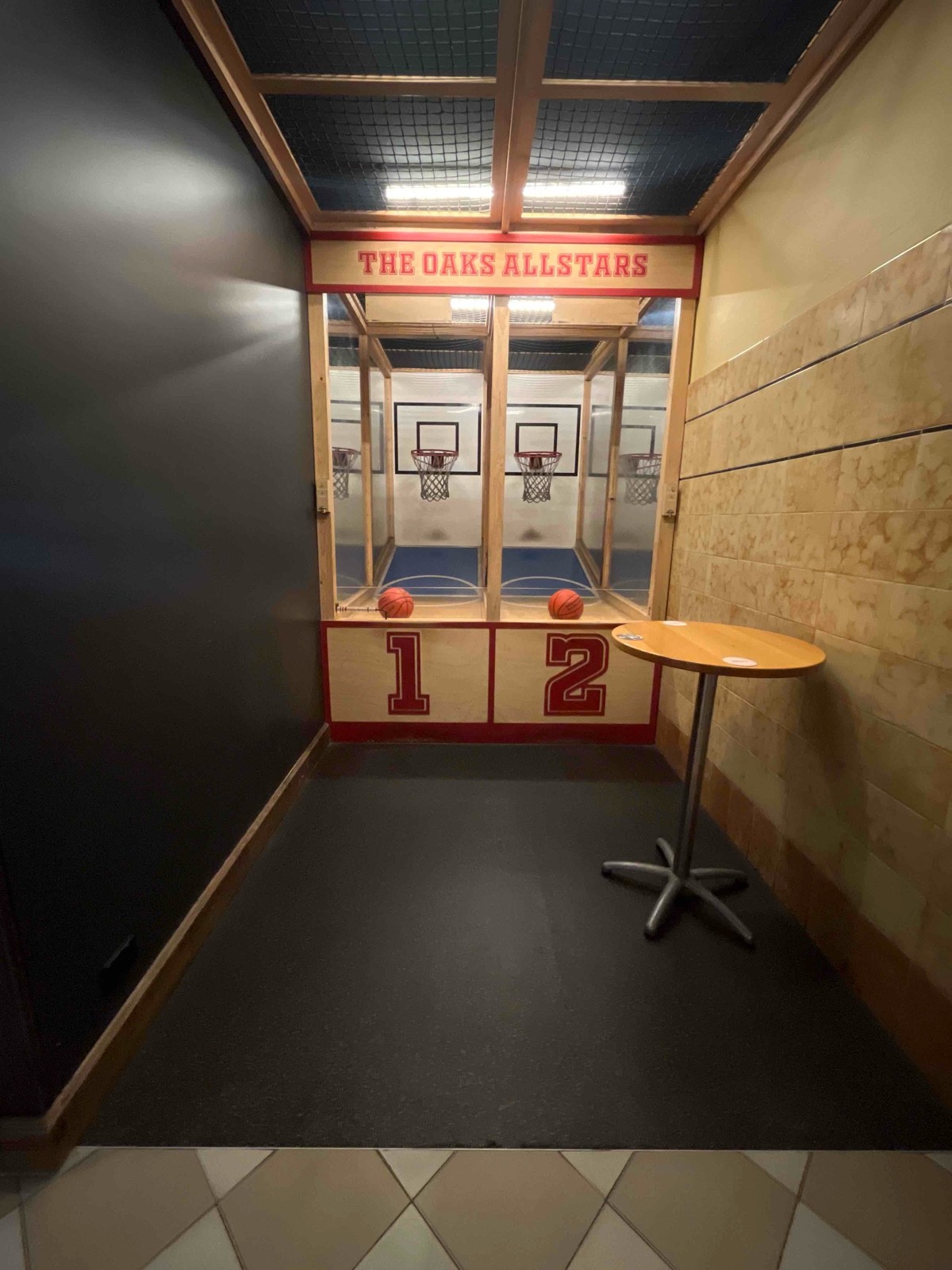 From after non accessible bathrooms facing left. Basketball hoops on wall ahead.