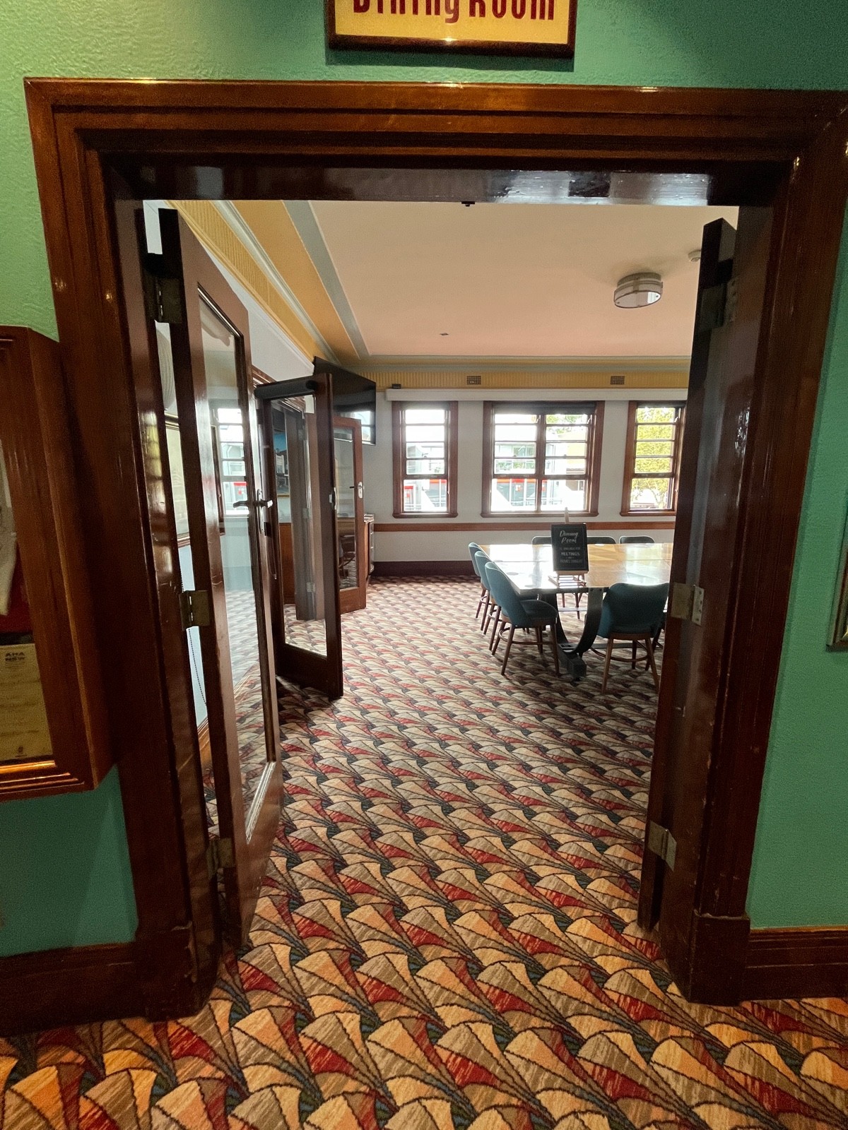 From beginning of bar facing right. Glass double doors with brown wooden frame. Turn silver handles and push from middle.