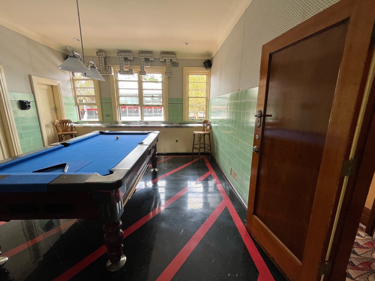 From door facing right. Pool table to left. High table with backed stools along wall behind.