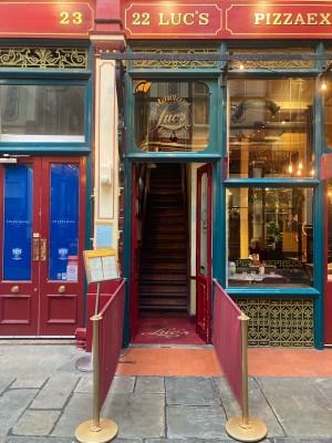 From street facing venue. Restaurant barriers along left and right. Doors at back.