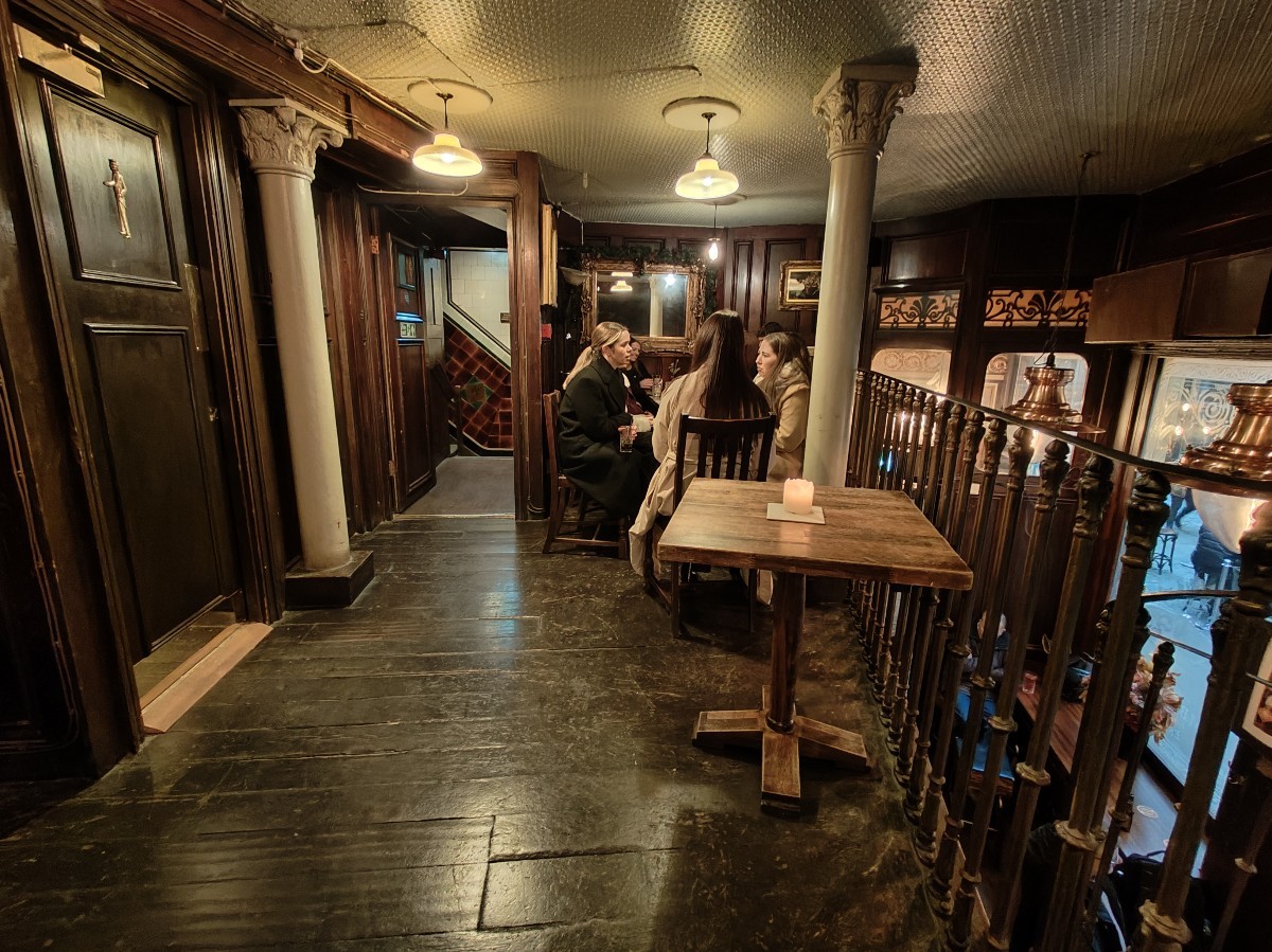 From top of stairs facing right. Tables and chairs ahead. Path ahead to side area on back left.