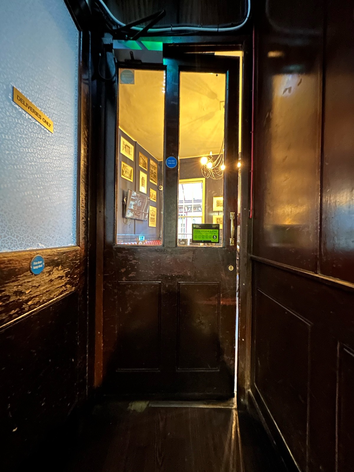 From top of stairs facing straight. Brown wooden door with glass panels. Push gold handle on right to open.