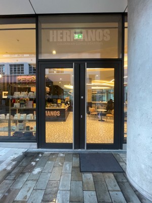 Facing double glass door with metal frames. Pull  metal handles in center to open.