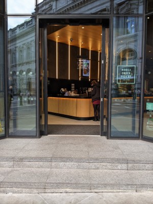 Two steps up to glass doors with metal frame. Doors slide away from centre to open.