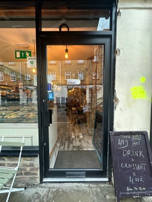 Glass door with black frame. Push handle from left to open. A-frame to right of door.