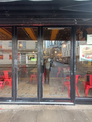 Glass door with black frame. Push black, metal handle in middle to open.