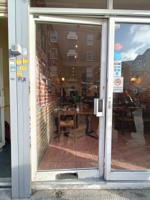 Glass door with white frame. Push white metal handle on right to open.