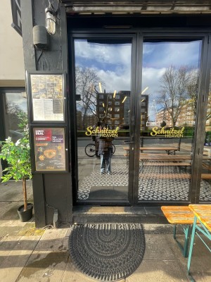 Glass door with black frame ahead. Push black metal handle on right to open.