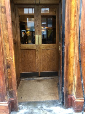 Wooden door with glass panel, push from left to open.