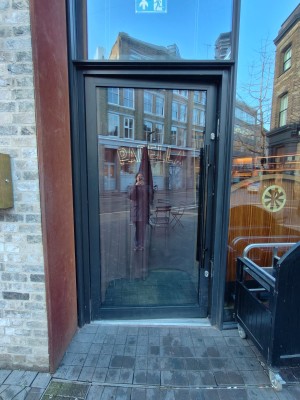 Glass door with dark grey frame. Push black handle on right to open.