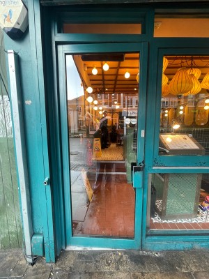 Glass door with green frame ahead. Pull green metal handle on right to open.