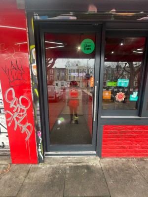 Glass door with black frame ahead. Push silver metal handle on right to open.