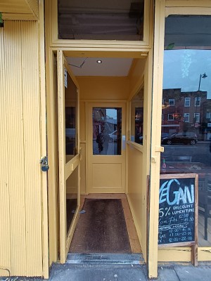 Glass door with yellow frame. Push yellow, metal handle on right to open.