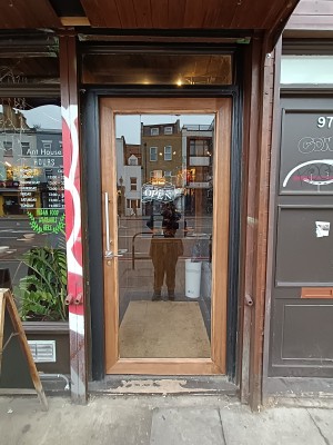 Glass door with brown frame. Push silver handle on left to open.
